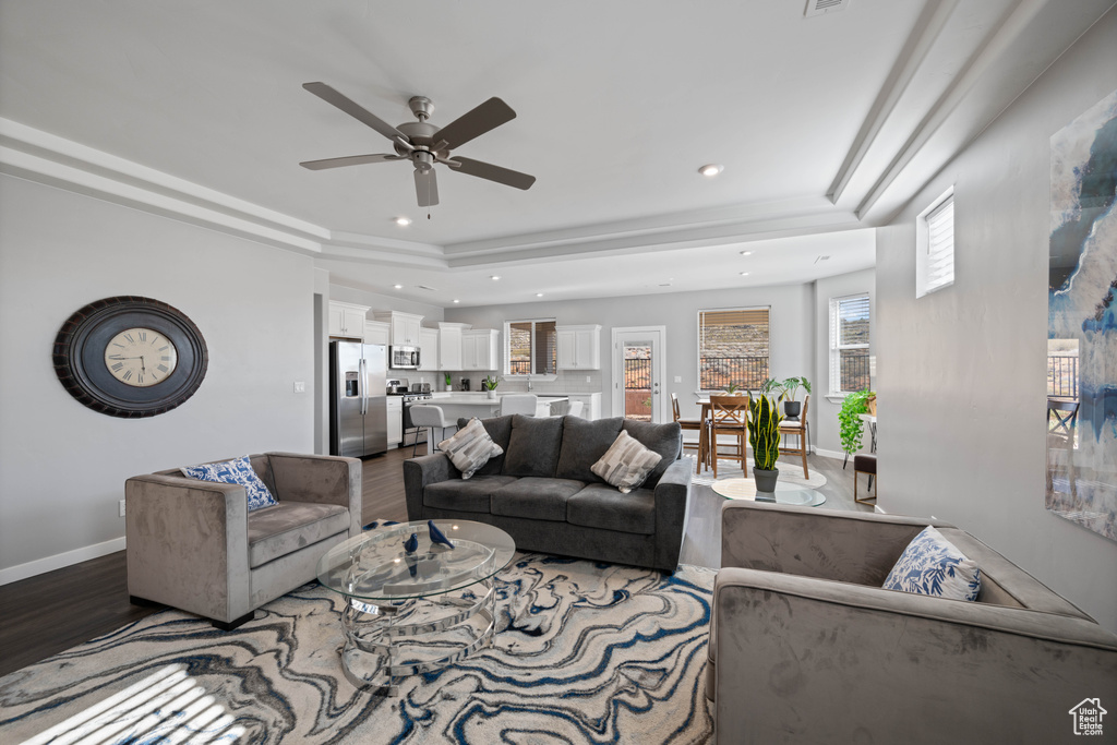 Living area featuring wood finished floors, a ceiling fan, recessed lighting, and a tray ceiling