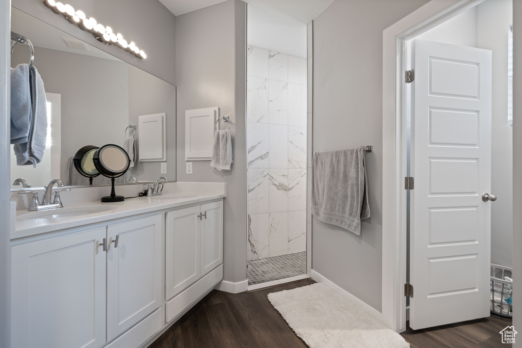 Bathroom featuring wood finished floors, a walk in shower, and double vanity