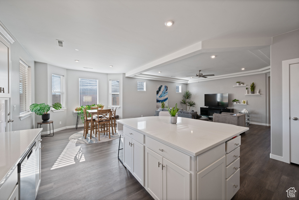 Kitchen featuring dark wood-style flooring, white cabinets, a ceiling fan, light countertops, and a center island