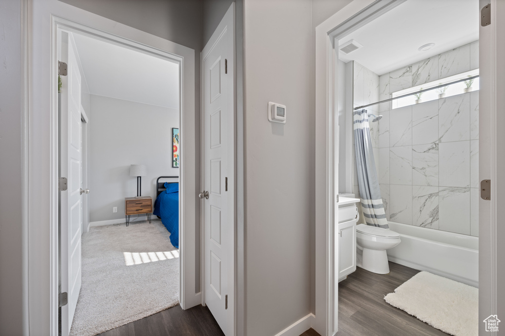 Full bath with wood finished floors, shower / bathtub combination with curtain, and vanity