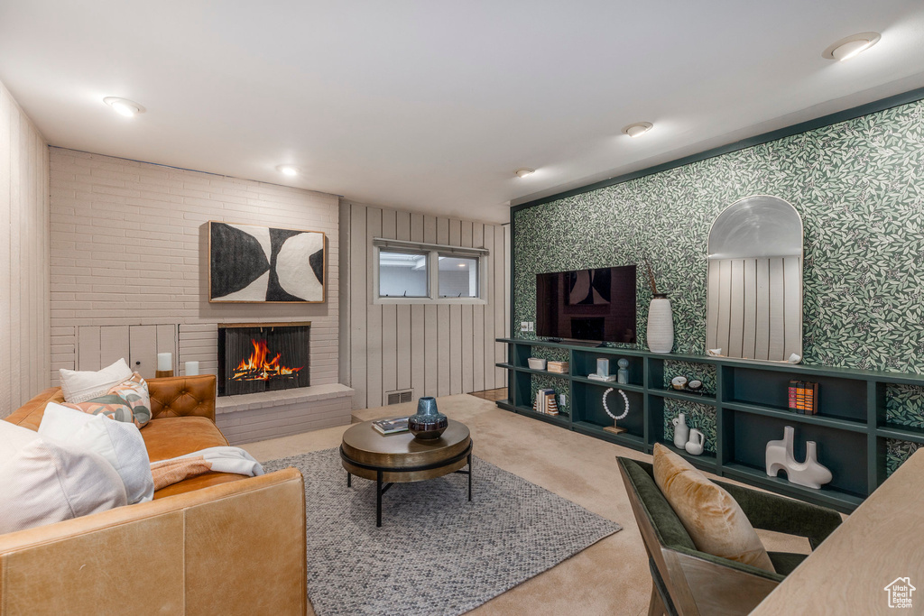 Living room featuring wallpapered walls, carpet floors, and a fireplace