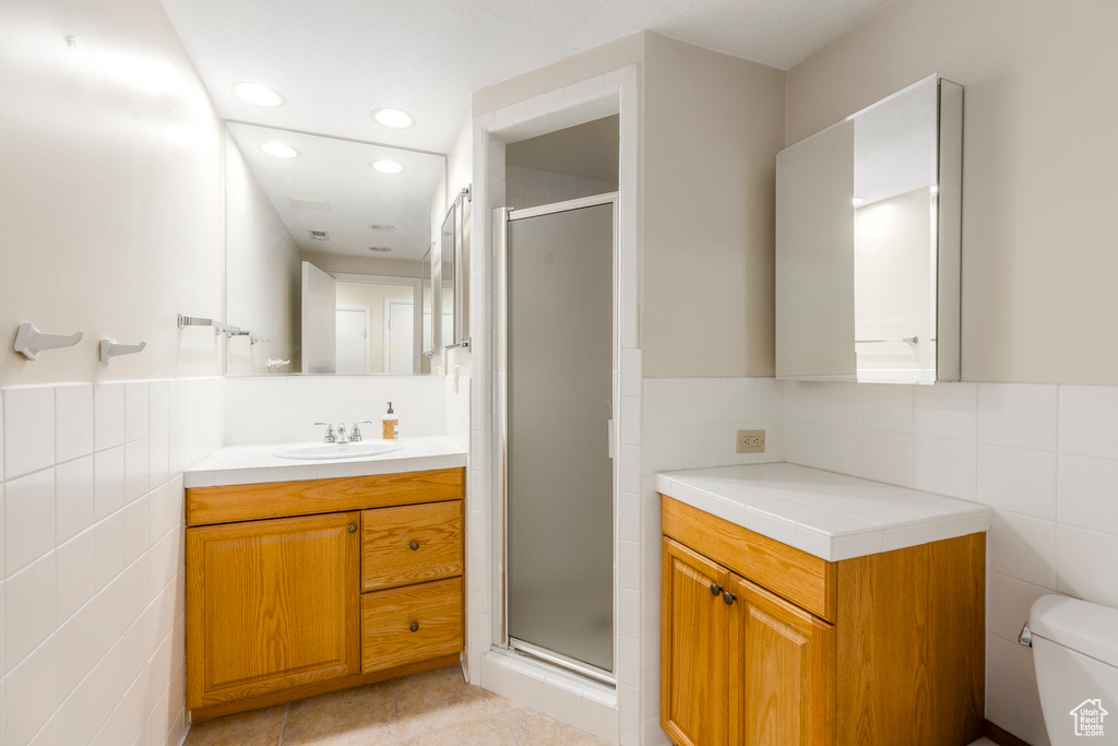 Bathroom with tile walls, vanity, a stall shower, recessed lighting, and decorative backsplash