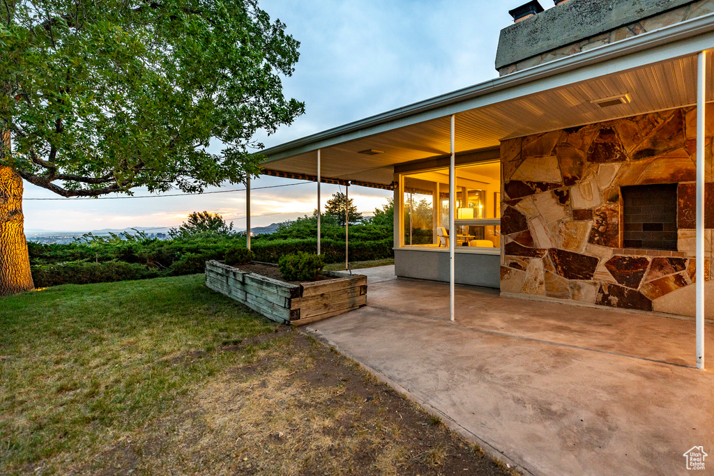 Yard at dusk featuring a patio area and a lawn