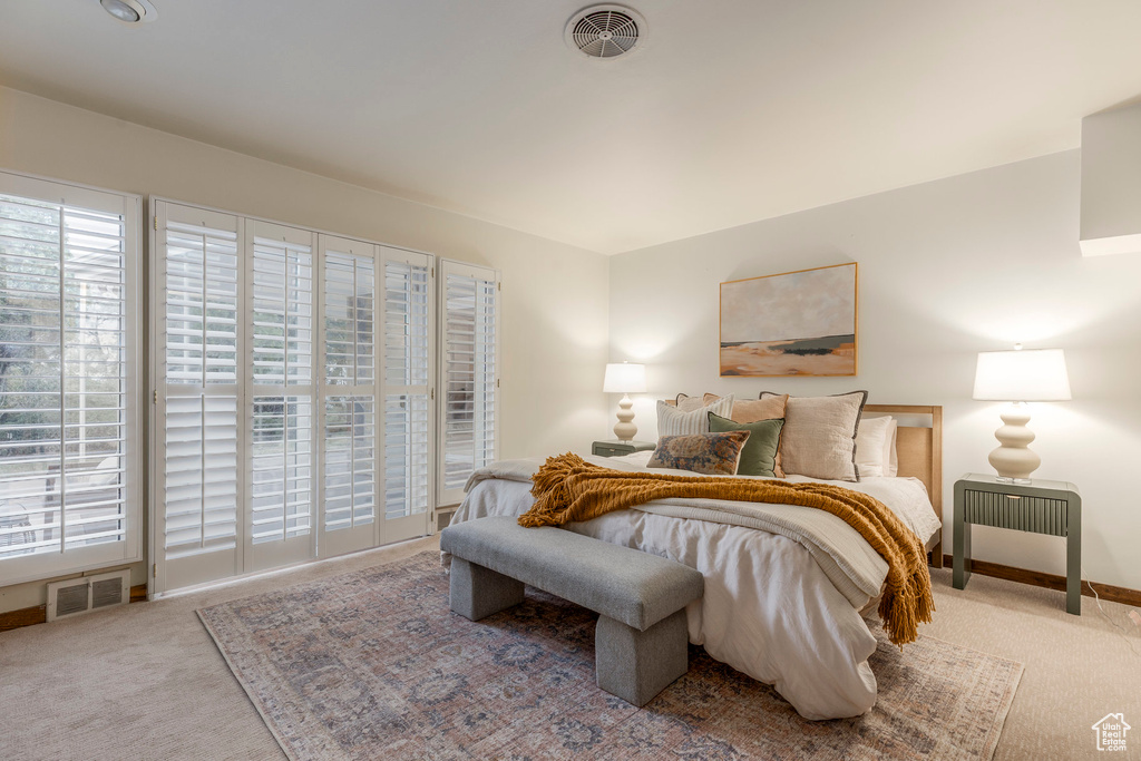 Carpeted bedroom featuring multiple windows and access to outside