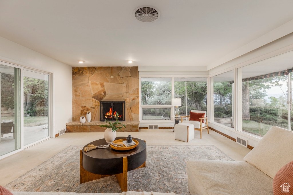 Living room featuring plenty of natural light, a stone fireplace, and recessed lighting