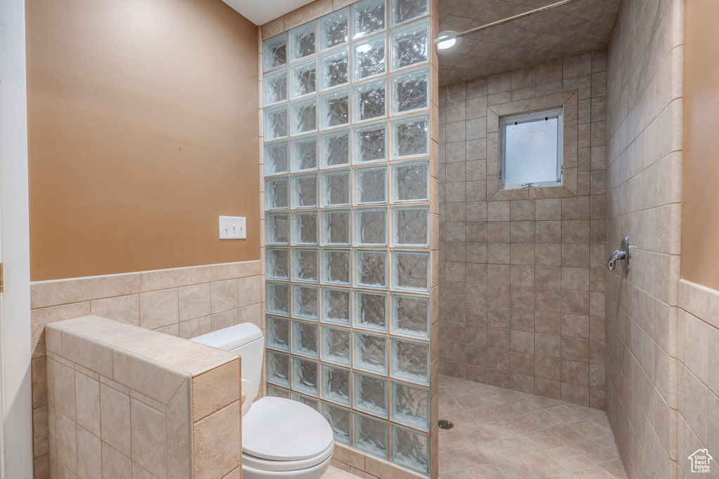 Full bath with tile walls, a walk in shower, and a wainscoted wall