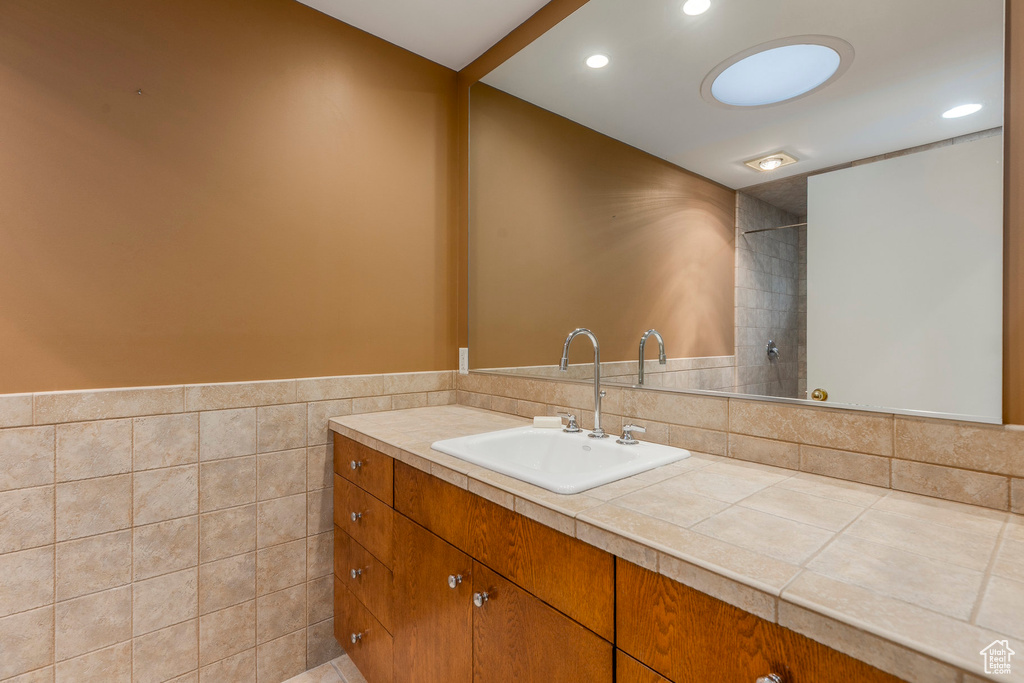 Bathroom with vanity, recessed lighting, and tile walls
