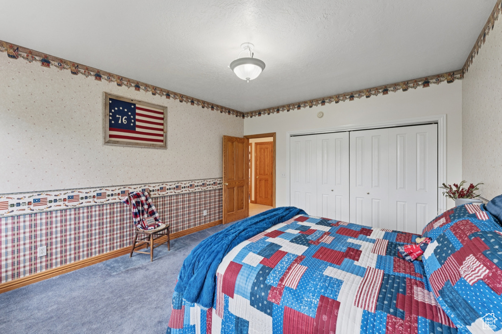 Carpeted bedroom featuring wallpapered walls and a closet