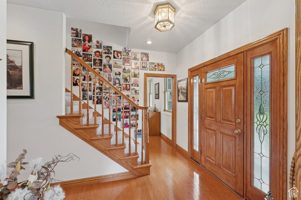 Foyer entrance featuring stairs, wood finished floors, and a textured ceiling