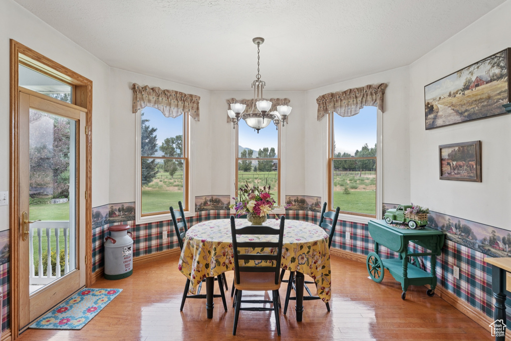 Dining space with a chandelier, wood finished floors, and wainscoting
