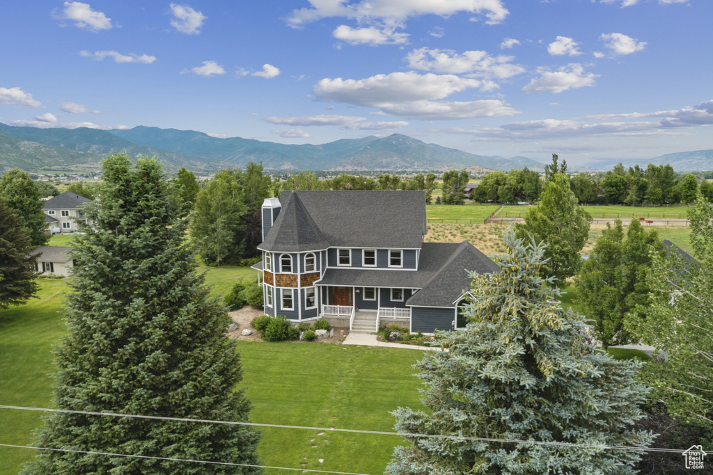Back of house featuring a porch, a lawn, a mountain view, and a chimney