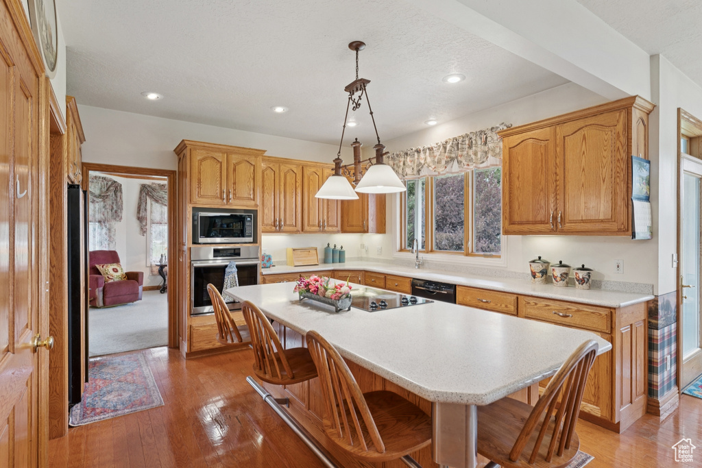 Kitchen featuring oven, black dishwasher, light countertops, a kitchen breakfast bar, and recessed lighting