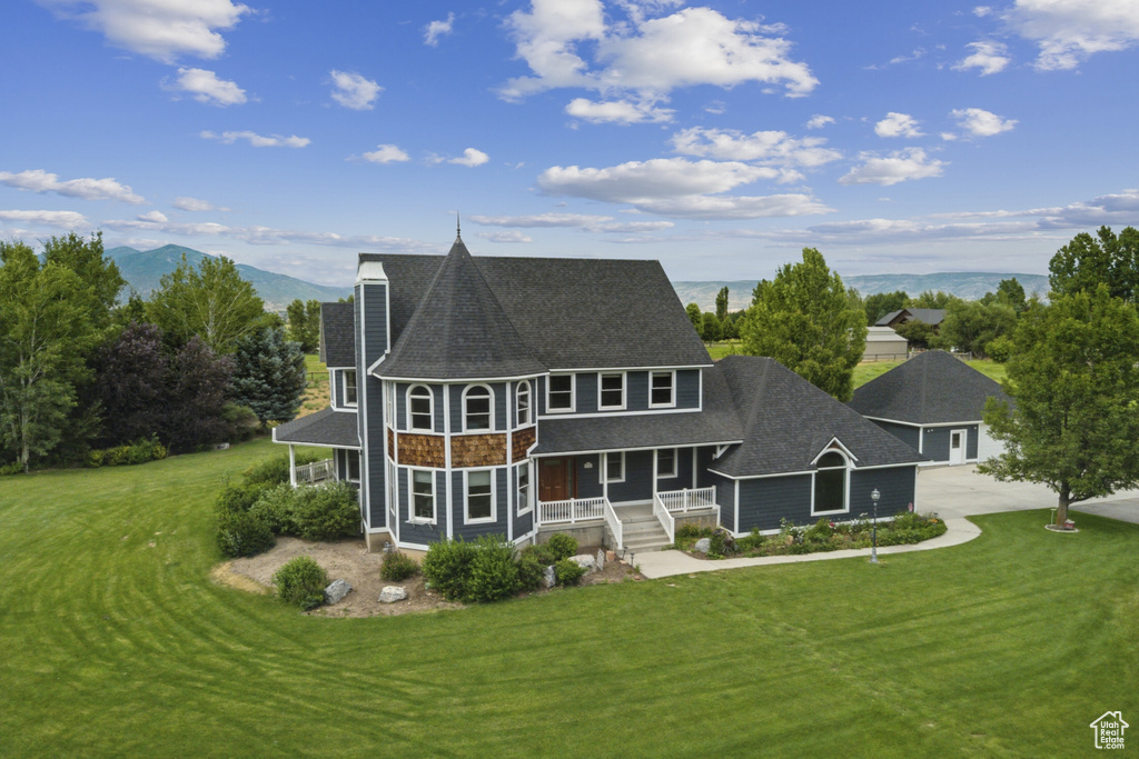 Rear view of house featuring covered porch, a shingled roof, concrete driveway, and a yard