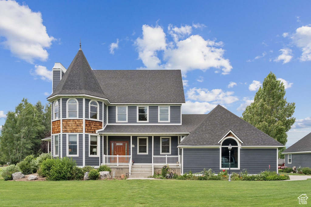 Victorian house with covered porch, a front yard, and roof with shingles