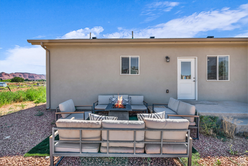 Rear view of house with an outdoor living space with a fire pit, stucco siding, and a patio