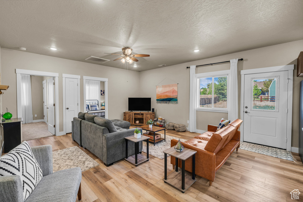 Living area featuring light wood finished floors, a ceiling fan, a textured ceiling, and recessed lighting