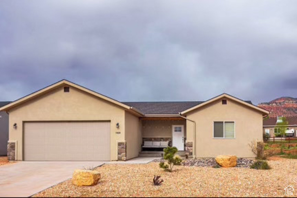 Ranch-style home featuring a garage, stucco siding, and concrete driveway