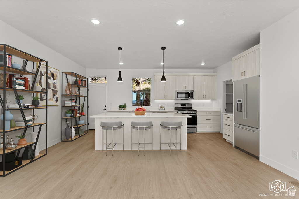 Kitchen with appliances with stainless steel finishes, light countertops, light wood finished floors, white cabinetry, and recessed lighting