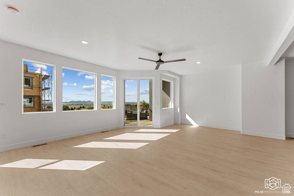 Unfurnished living room featuring light wood-style flooring, a ceiling fan, and recessed lighting