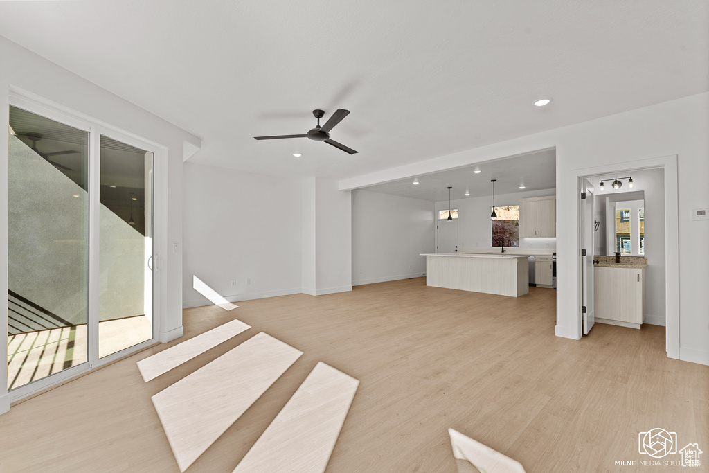 Unfurnished living room with a ceiling fan, recessed lighting, and light wood-style floors