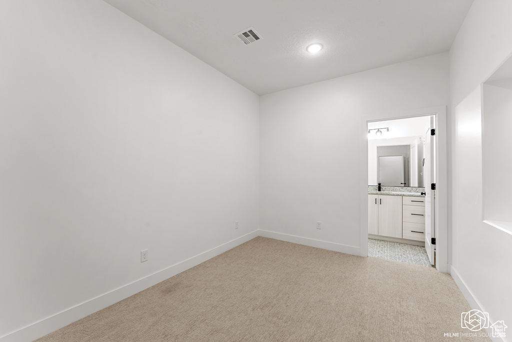 Unfurnished bedroom featuring light colored carpet, ensuite bath, bar area, and recessed lighting