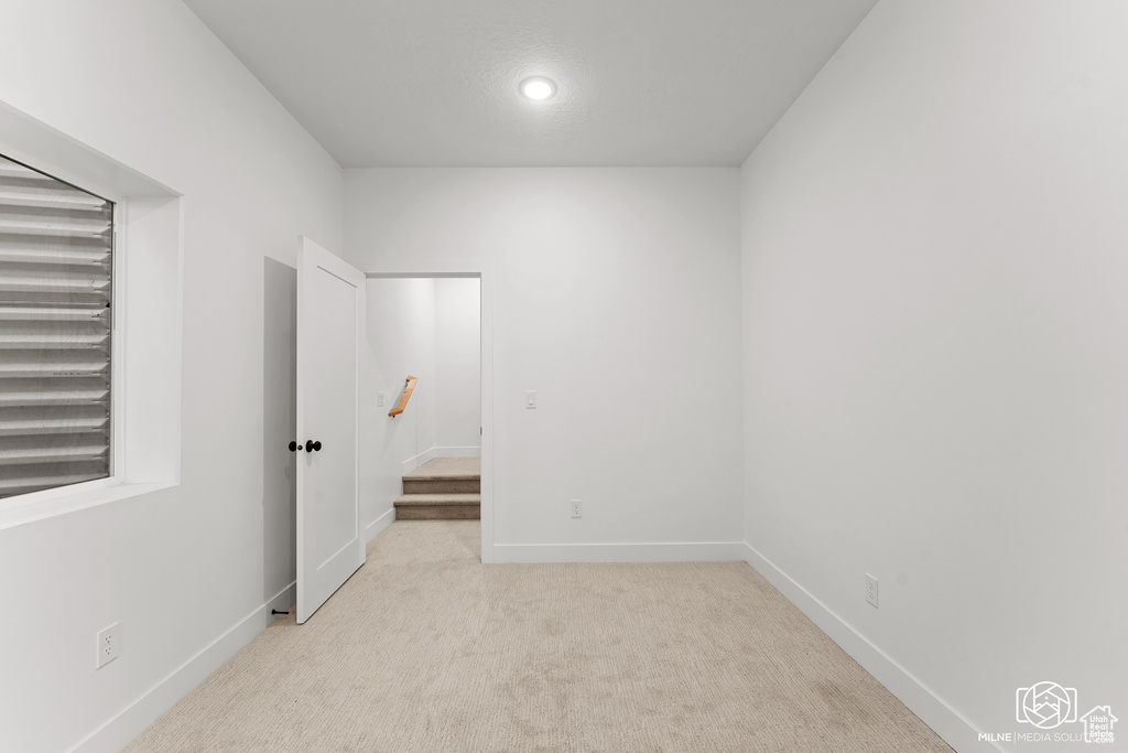 Unfurnished bedroom with light carpet and recessed lighting