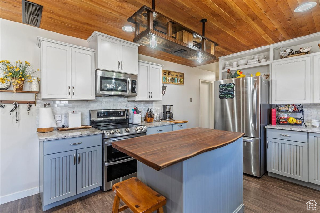 Kitchen featuring stainless steel appliances, butcher block counters, wooden ceiling, open shelves, and tasteful backsplash