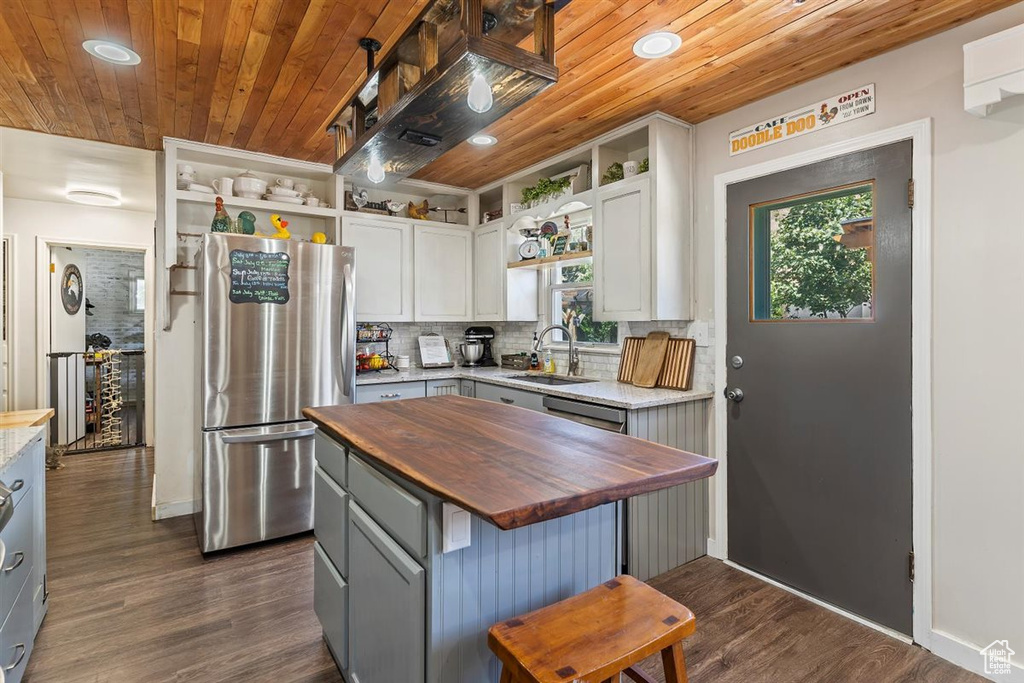 Kitchen featuring butcher block countertops, appliances with stainless steel finishes, open shelves, wooden ceiling, and dark wood-style flooring