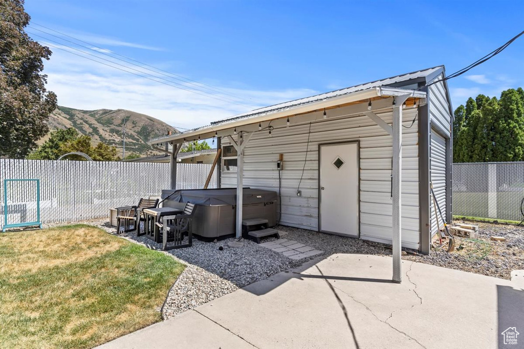 View of outdoor structure with a hot tub, a fenced backyard, and a mountain view