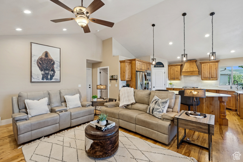 Living area featuring light wood-style flooring, vaulted ceiling, ceiling fan, and recessed lighting