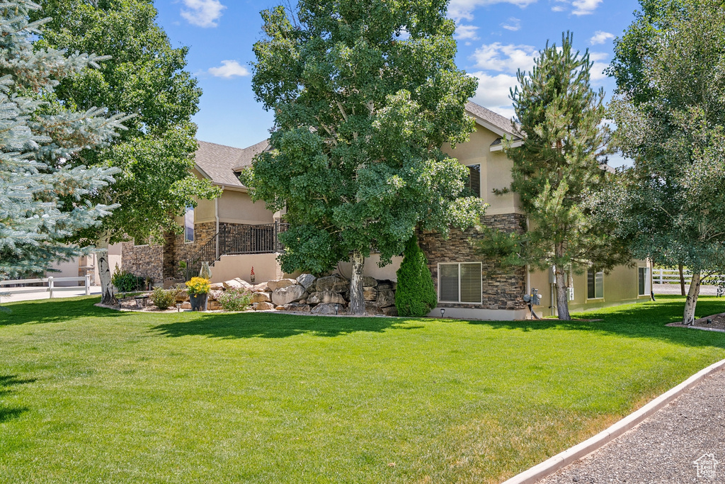 Obstructed view of property featuring stone siding, stucco siding, and a front lawn