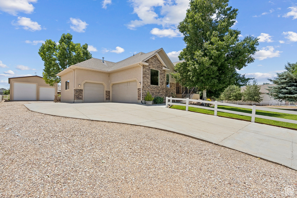 View of front of home featuring stone siding, driveway, an attached garage, and stucco siding