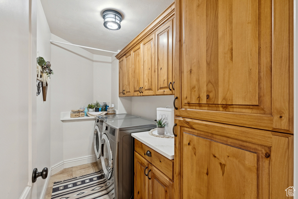 Laundry room with independent washer and dryer, cabinet space, and tile patterned floors