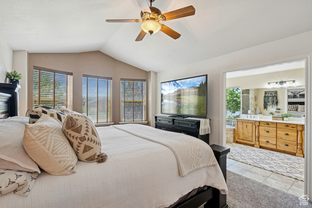 Tiled bedroom featuring vaulted ceiling, ensuite bath, and a ceiling fan