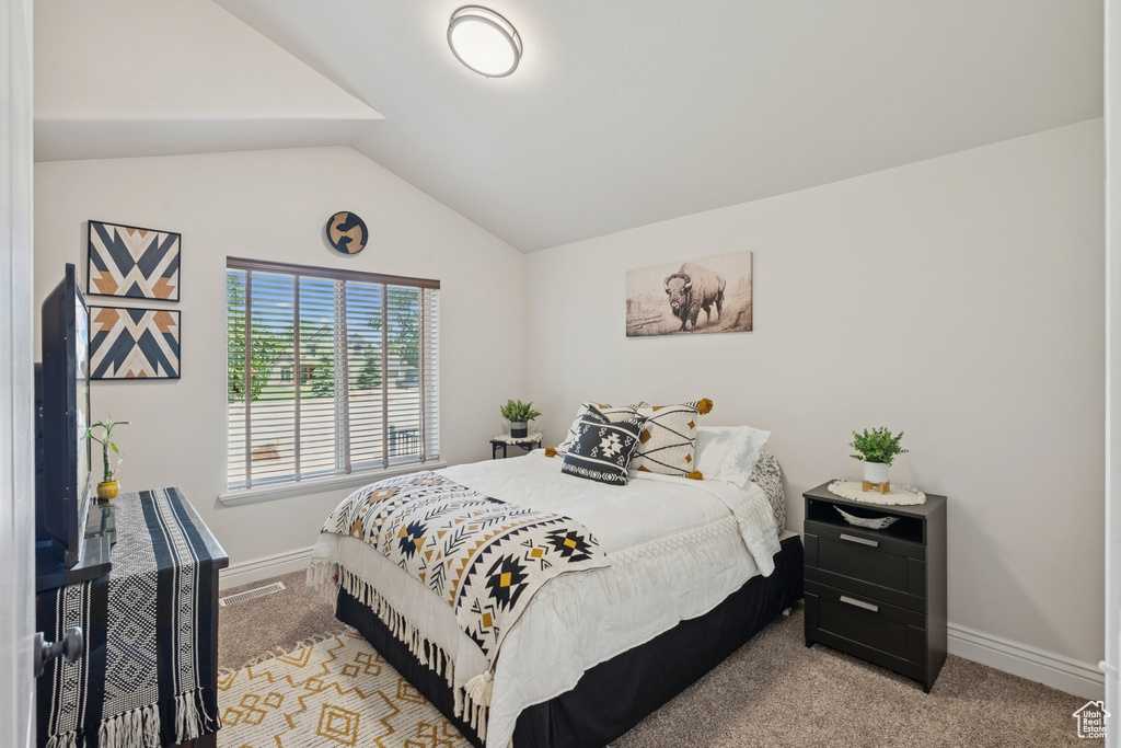Bedroom with light colored carpet and lofted ceiling