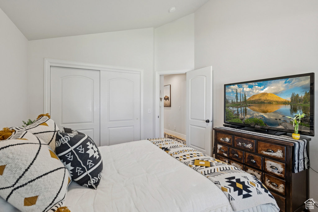 Bedroom with a closet and high vaulted ceiling
