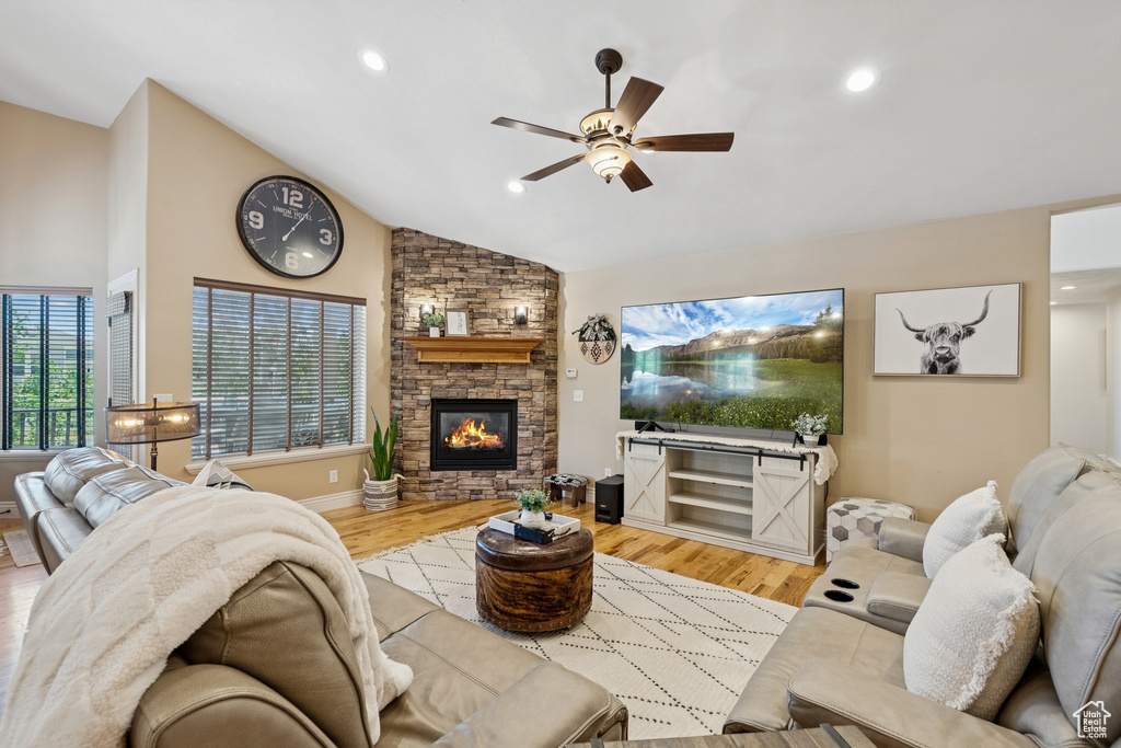 Living area with vaulted ceiling, a ceiling fan, a fireplace, light wood-style flooring, and recessed lighting