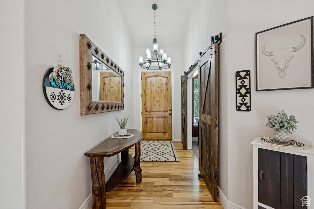 Entryway featuring a barn door, a chandelier, and light wood-style flooring