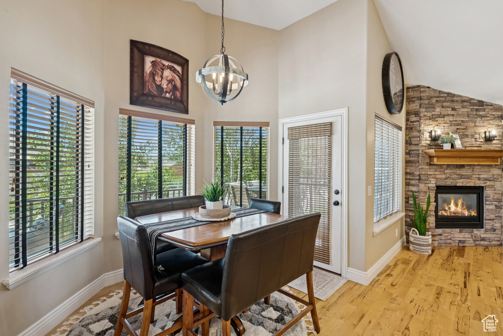 Dining room with plenty of natural light, a chandelier, high vaulted ceiling, and wood finished floors