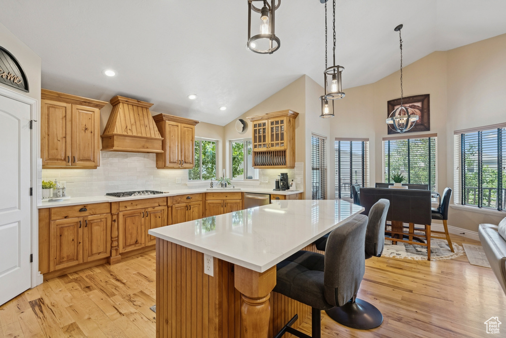 Kitchen featuring stainless steel dishwasher, gas stovetop, custom range hood, light wood-style flooring, and light countertops