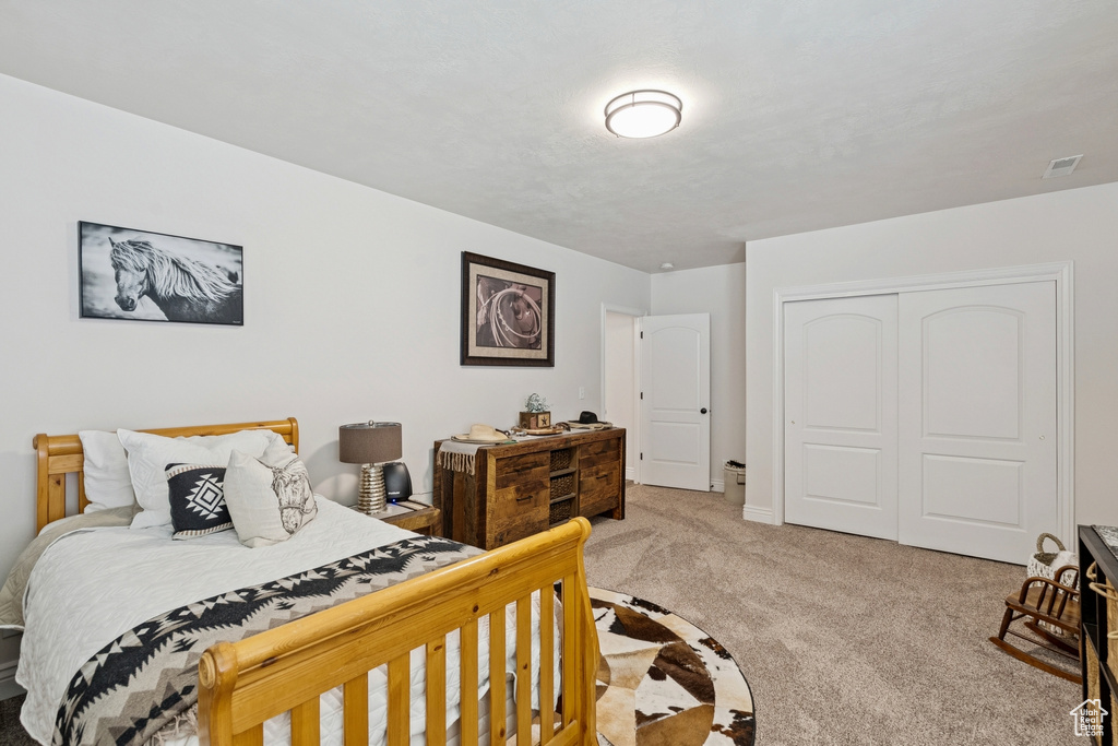 Carpeted bedroom with a closet and baseboards