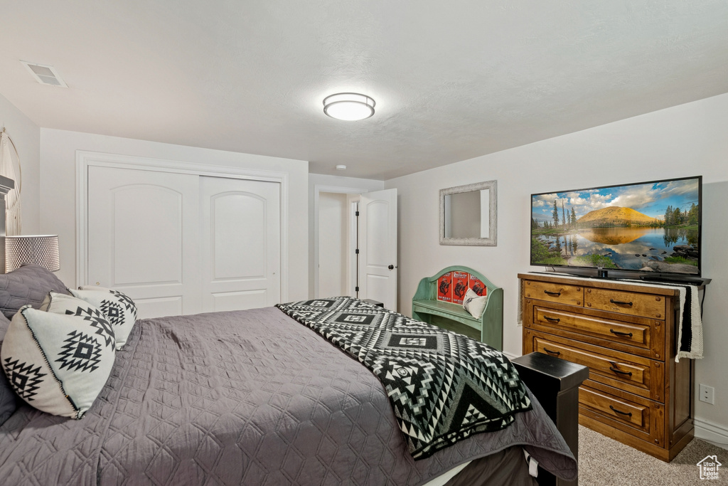 Bedroom with light carpet and a closet