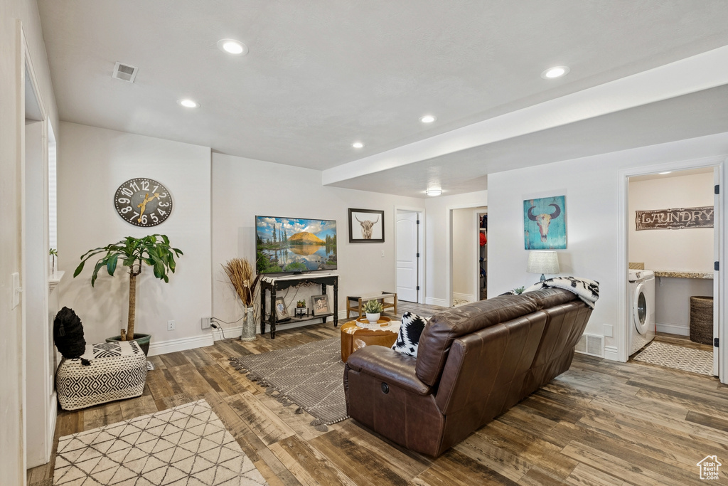 Living room with washer / dryer, wood finished floors, and recessed lighting