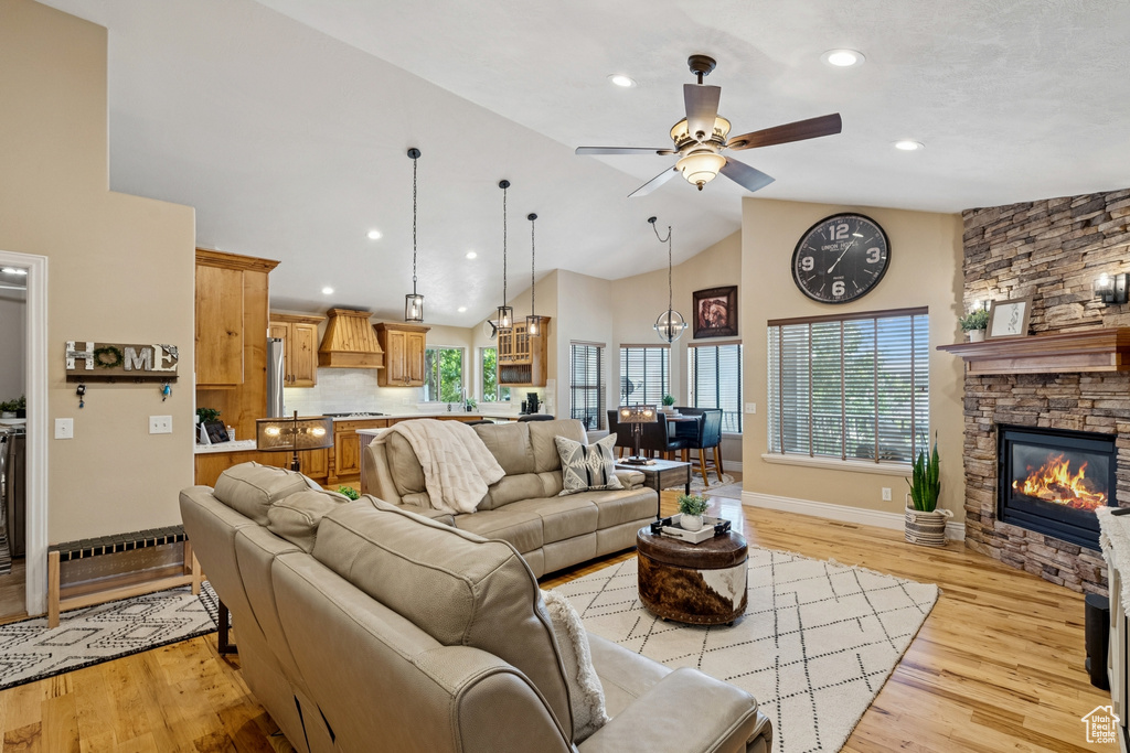 Living area featuring high vaulted ceiling, light wood-type flooring, a ceiling fan, recessed lighting, and a stone fireplace
