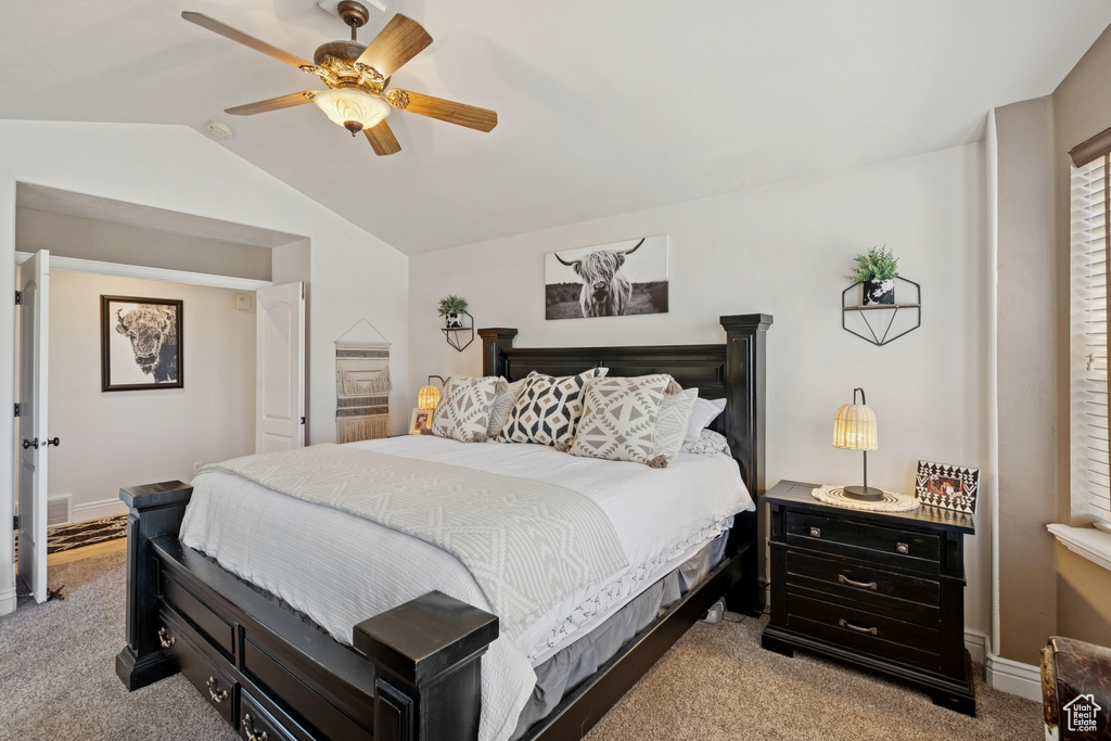 Bedroom with light colored carpet, vaulted ceiling, and a ceiling fan