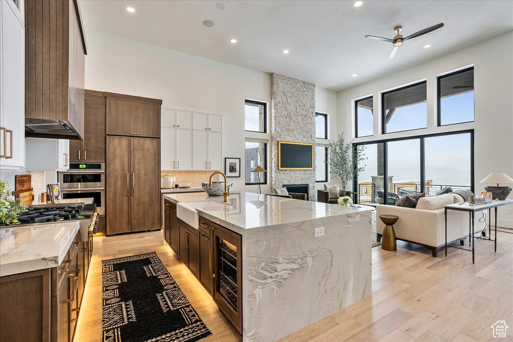 Kitchen with a high ceiling, light wood-style flooring, ceiling fan, open floor plan, and recessed lighting