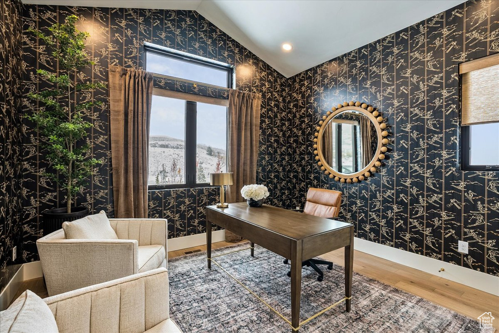 Office with wallpapered walls, wood finished floors, vaulted ceiling, and plenty of natural light
