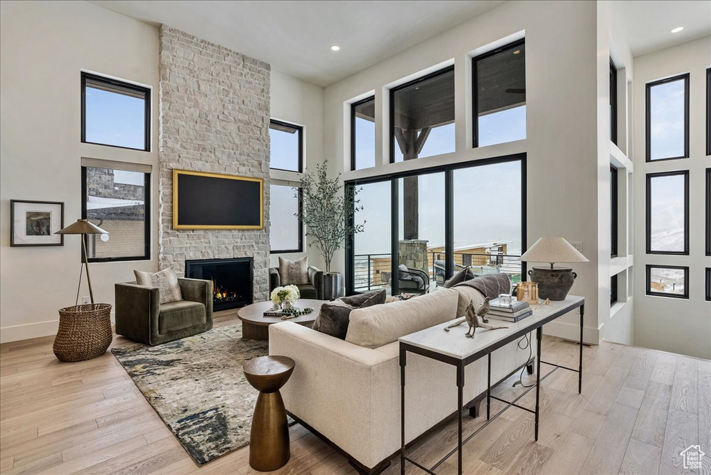 Living area featuring wood finished floors, a high ceiling, a fireplace, and recessed lighting