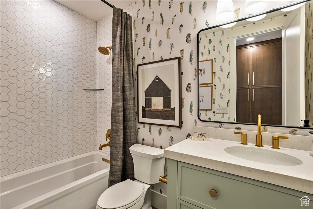 Bathroom featuring shower / bath combo with shower curtain, vanity, and wallpapered walls