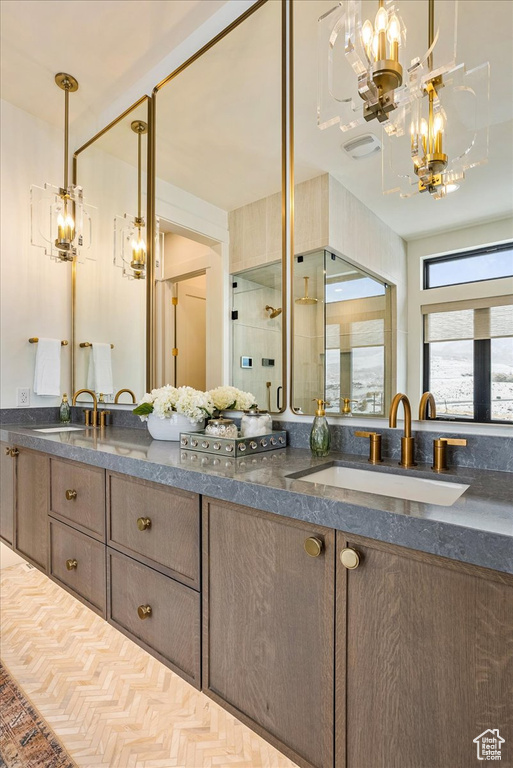 Full bath with a chandelier, double vanity, and an enclosed shower